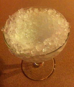 Step 1 of the ice shell: Pack the glass with finely crushed ice, pressing down in the center with a spoon to create the "shell."